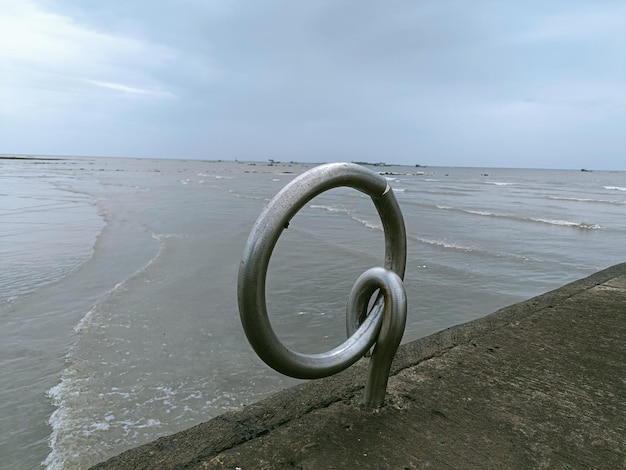 Metallic structure on beach against sky