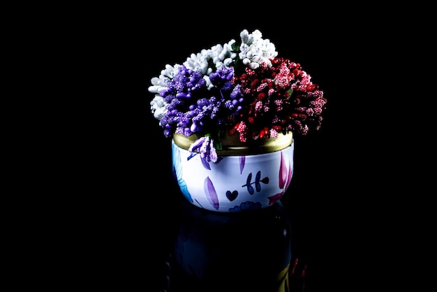 Metallic vase with white red blue flowers with reflection black background isolated