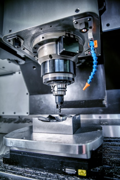 Photo metalworking cnc milling machine. cutting metal modern processing technology. small depth of field. warning - authentic shooting in challenging conditions. a little bit grain and maybe blurred.