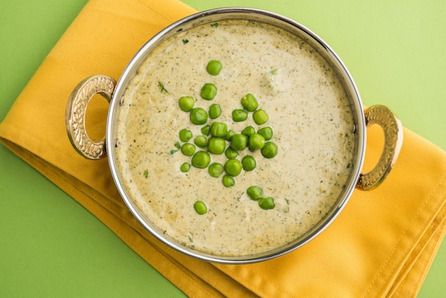 Methi Matar Malai is a popular North Indian Main Course served in a Karahi over green background, selective focus