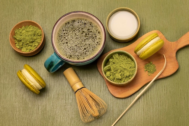 Metinglepel groen matcha poeder en macaron koekjes op houten plank Melk in schaal Matcha thee in kopje