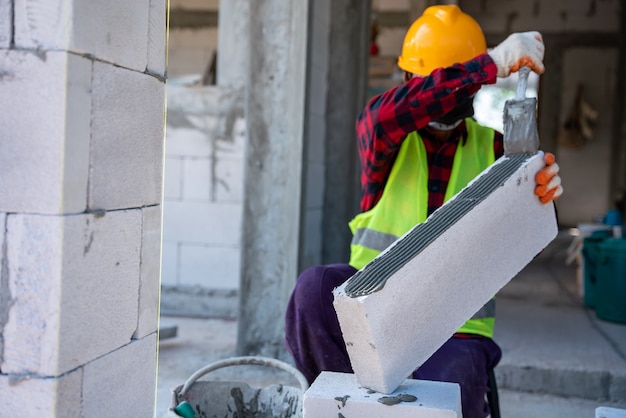 Metselaar bouwer werken geautoclaveerd belucht met zelfklevende gips betonblokken. Muren, plaatsen van bakstenen bij onvoltooide woningbouw, Engineering en constructies concepten.