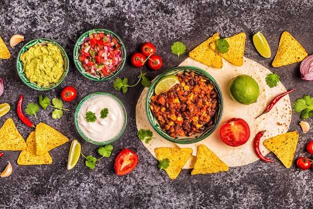 Mexicaans eten concept: tortilla's, nacho's met guacamole, salsa, chili con carne, bovenaanzicht.
