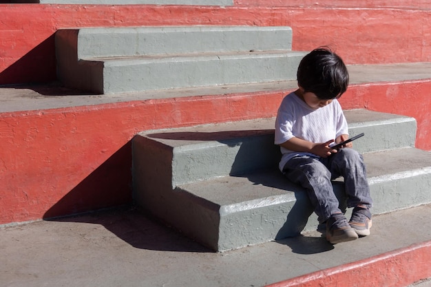 Mexicaans kind dat buiten met een smartphone speelt