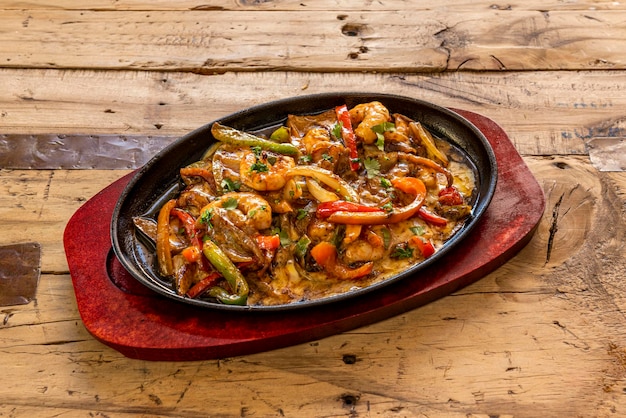 Mexicaans populair recept dienblad van draad met garnalen Groenten gebakken met kaas en garnalen geserveerd in een gietijzeren bakje