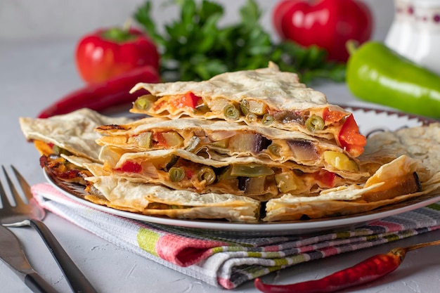 Foto mexicaans tortilla-quesadilla-voorgerecht met groenten en kaas in plaat op lichtgrijze achtergrond