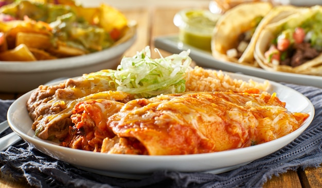 Foto mexicaanse enchiladaschotel met rode saus, gebakken bonen en rijst