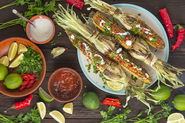 Mexicaanse gegrilde maïs met hete chilisaus op de eettafel, bovenaanzicht