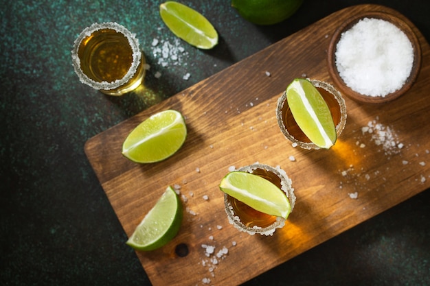 Mexicaanse gouden Tequila geschoten met limoen en zout op donkere stenen achtergrond Bovenaanzicht plat lag achtergrond