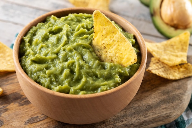 Mexicaanse guacamole met nacho-chip in houten kom op rustieke houten tafel Bovenaanzicht Traditioneel Mexicaans eten