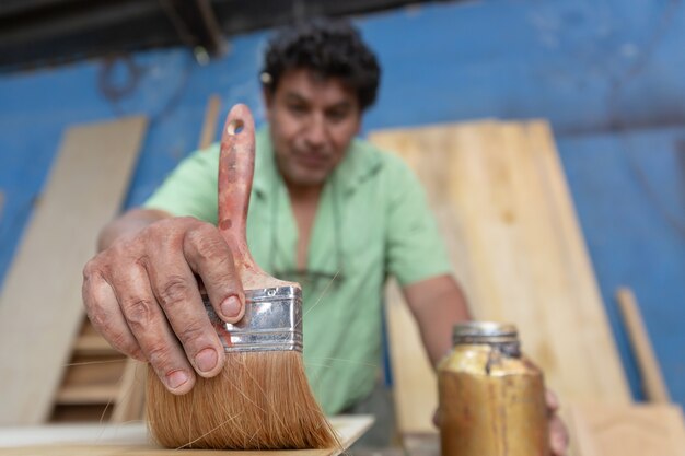 Mexicaanse houtbewerker, timmerman lakt in zijn atelier