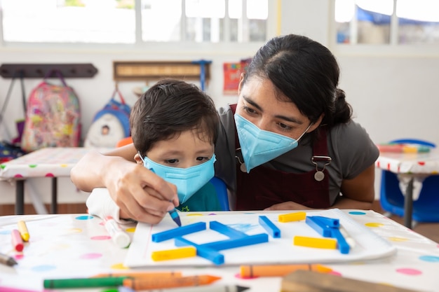 Mexicaanse leraar en kind met maskers op school na covid-19 quarantaine