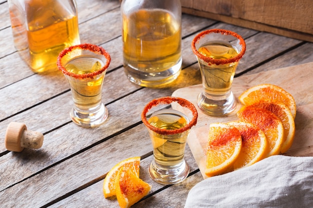 Mexicaanse mezcal of mescal geschoten met chilipeper en schijfje sinaasappel. Alcoholische drank vergelijkbaar met tequila