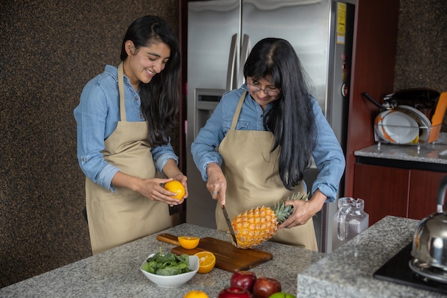 Mexicaanse moeder en dochter die fruit in de keuken snijden en lachen, familie en moederdag