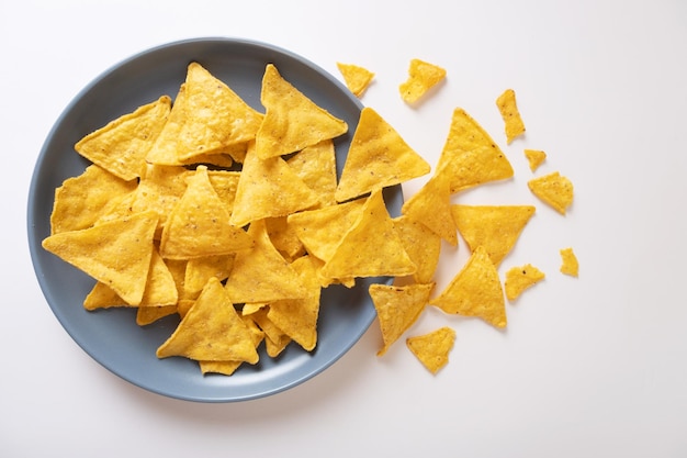 Mexicaanse nacho maïschips gegoten uit een blauw bord op een witte tafel Een gerecht uit de Latijns-Amerikaanse keuken