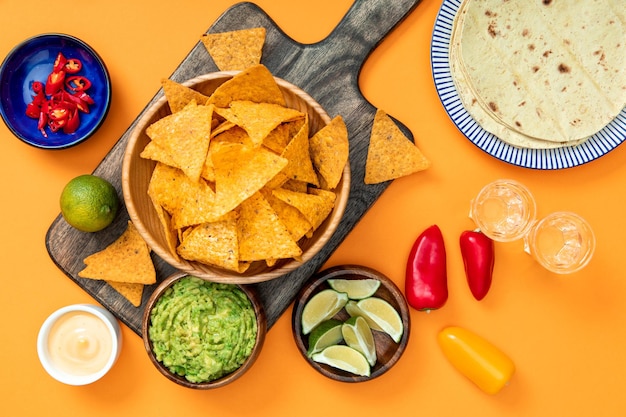 Mexicaanse nacho's geserveerd op houten snijplank met guacamole kaassaus pepers limoenen Tequila
