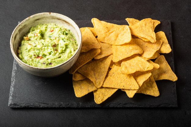 Mexicaanse nachos chips en bowl met huisgemaakte verse guacomole saus gemaakt van avocado en limoen