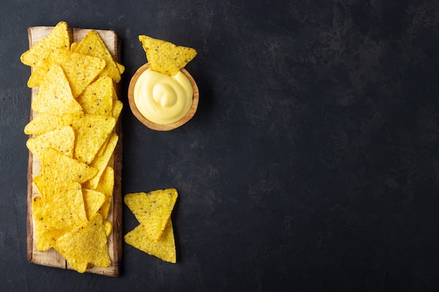 Mexicaanse nachos chips met kaassaus op zwarte achtergrond. bovenaanzicht met kopie ruimte.