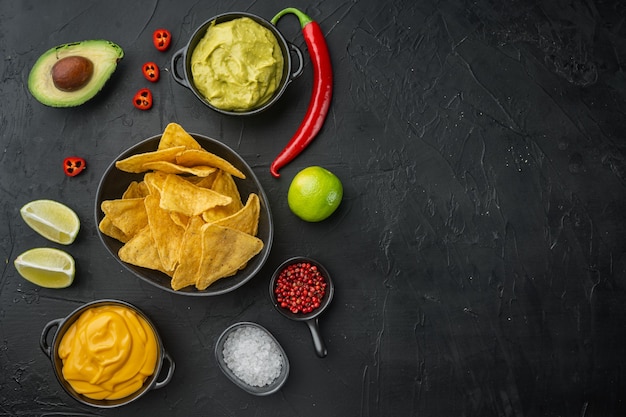 Mexicaanse nachoschips met dipsaus, op zwarte tafel, bovenaanzicht of plat leggen