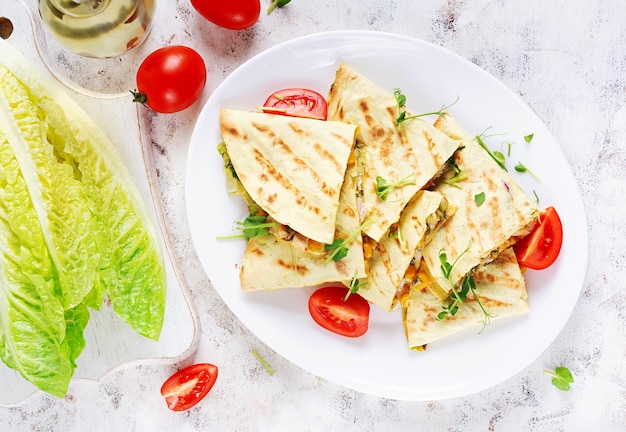 Foto mexicaanse quesadilla verpakt met kippenmaïs en zoete peper op een wit bord