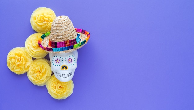 Mexicaanse schedel met hoed met gele bloemen van papier cempasuchil op violet