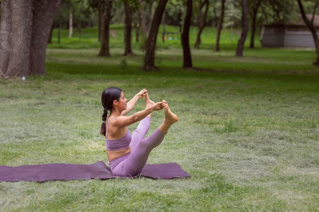 Mexicaanse vrouw doet yoga-oefeningen in het park op groen gras