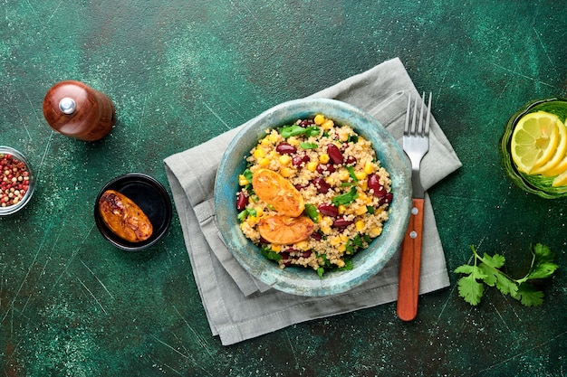 Mexicaanse zwarte bonen maïs quinoa salade met gekarameliseerde citroen in oude vintage kleikom op een donkergroene betonnen ondergrond. Traditioneel Mexicaans keukengerecht. Bovenaanzicht,