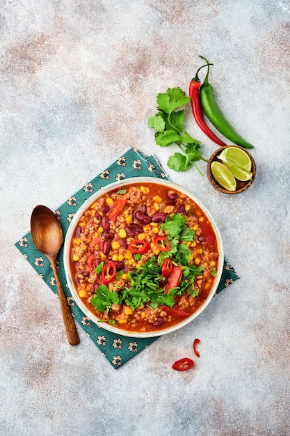 Photo mexican black bean soup with minced meat, tomato, cilantro, avocado and vegetables stew