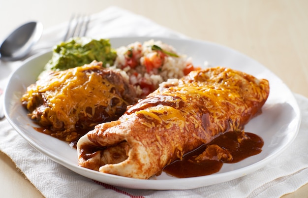 Mexican burrito platter with red enchilada sauce, fried beans,\
rice and guacamole