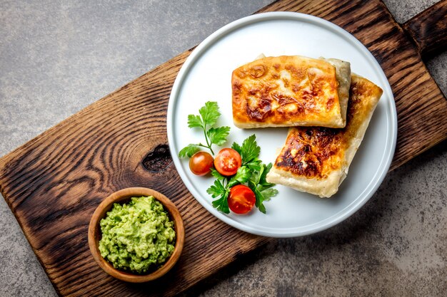 Il chimichanga messicano su un piatto bianco è servito con guacamole