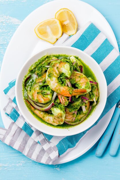 Photo mexican cuisine aguachile de camaron prawns aguachile shrimps eviche cebiche with cucumber lemon and purple onion top view blue background