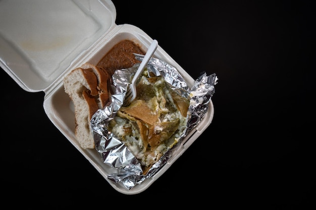 A Mexican food Chicken Chilaquiles with green sauce on disposable plate for home delivery