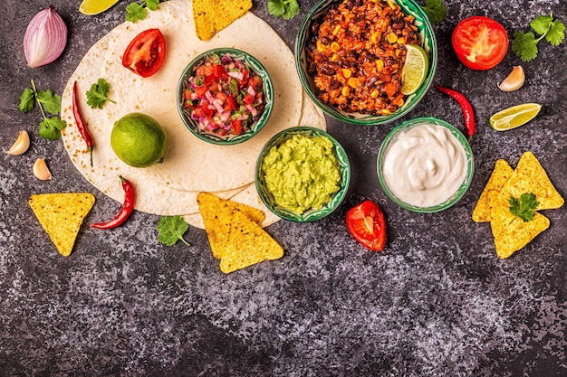 Foto concetto di cibo messicano: tortillas, nachos con guacamole, salsa, chili con carne, vista dall'alto.
