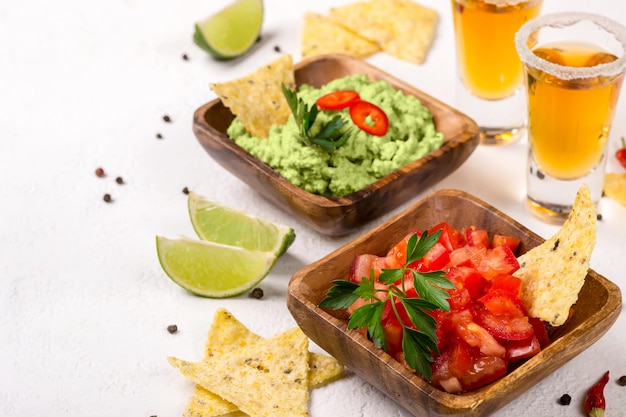 Mexican food sauce guacamole salsa chips and tequila shots with lime Selective focus