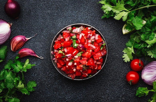 Mexican food Spicy salsa sauce with tomatoes chili peppers onion garlic and cilantro black table background top view