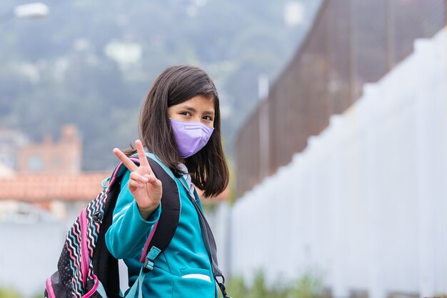 Mexican girl excited on back to school wearing protective face mask after coronavirus lockdown