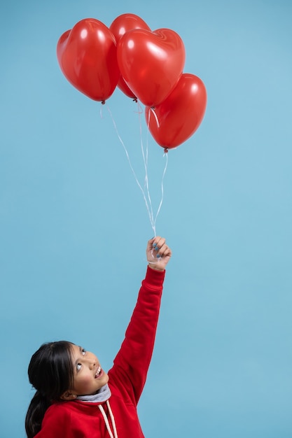 Mexican girl holding a bunch of red heart balloon