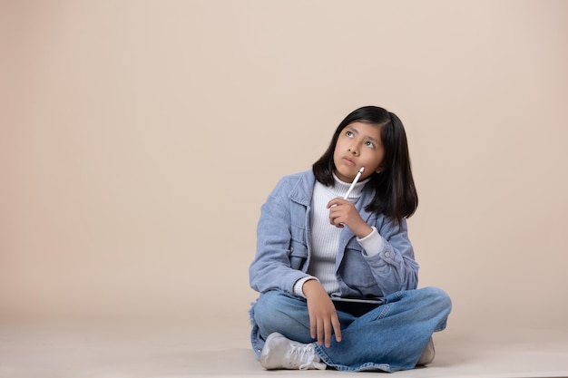 Mexican girl sitting on the floor thinking expression with tablet and stylus pen