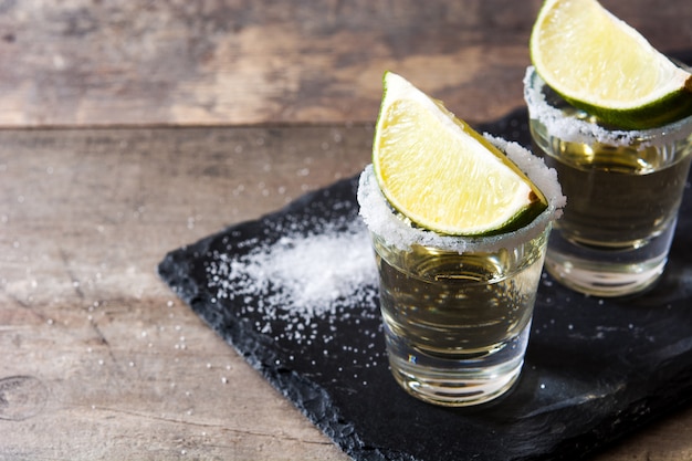 Photo mexican gold tequila in glass with lime and salt on wooden table