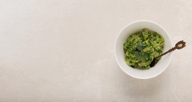 Mexican guacamole sauce in a white bowl on a concrete background, top , copy space