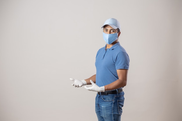 Mexican messenger wearing gloves and face mask on gray wall isolated