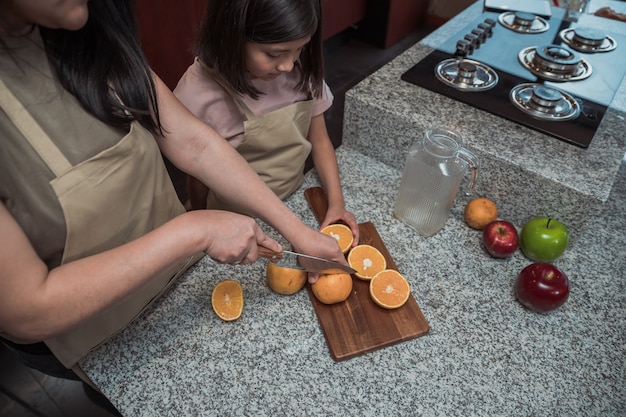 Mexican mother and daughter preparing orange juice in the kitchen, close uo