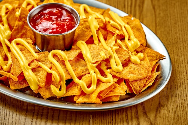 Mexican nachos chips with cheese and red sauce Snack Closeup selective focus Noise added in postproduction