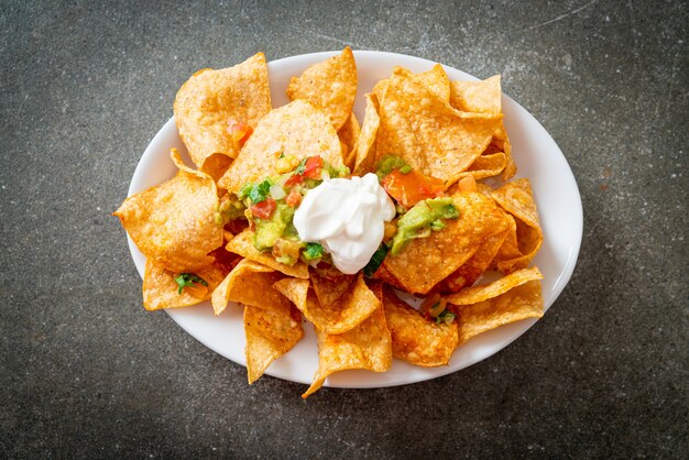 Mexican nachos tortilla chips with jalapeno, guacamole, tomatoes salsa and dip