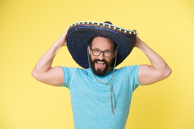 Photo mexican party man on smiling face in sombrero hat celebrating yellow background guy with beard looks festive in sombrero fest and holiday concept man in festive mood at party celebrating