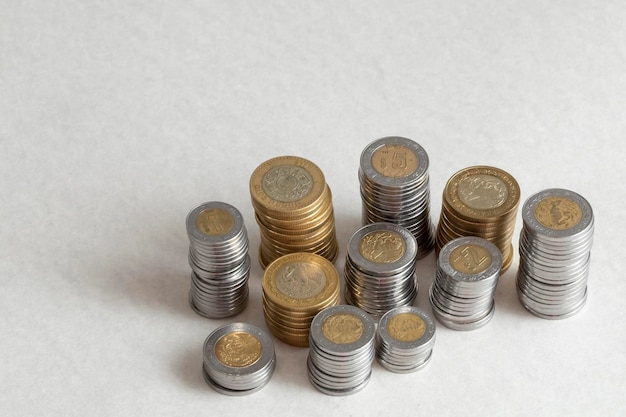 Mexican peso coins of different denominations stacked on a table with copy space