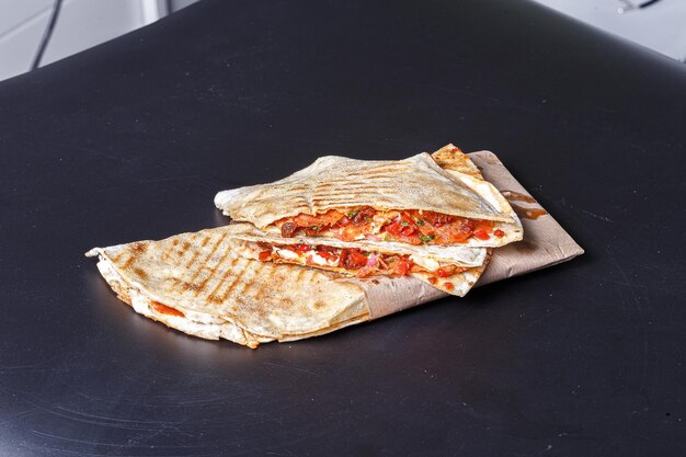 mexican quesadilla, homemade, in wrapping paper, on a black isolated background