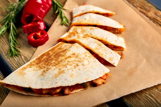 Mexican quesadilla with chicken cheese and peppers on wooden table