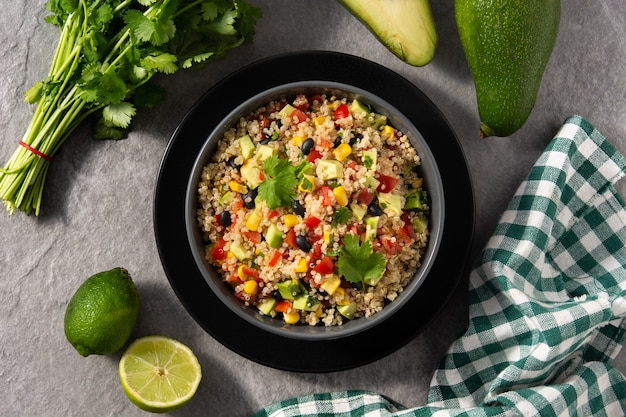 Mexican salad with quinoa in bowl on wooden table.