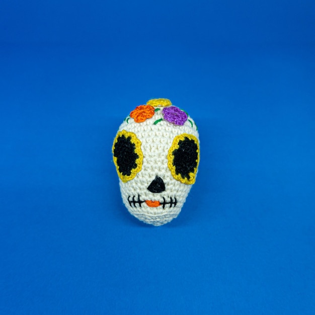 Mexican skull amigurumi, on blue background.